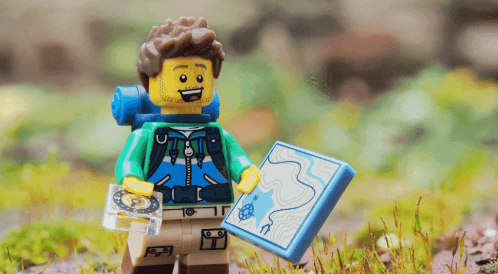 Lego man geocaching with his compass and map